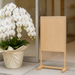 白い胡蝶蘭の鉢植えと木製の立て看板