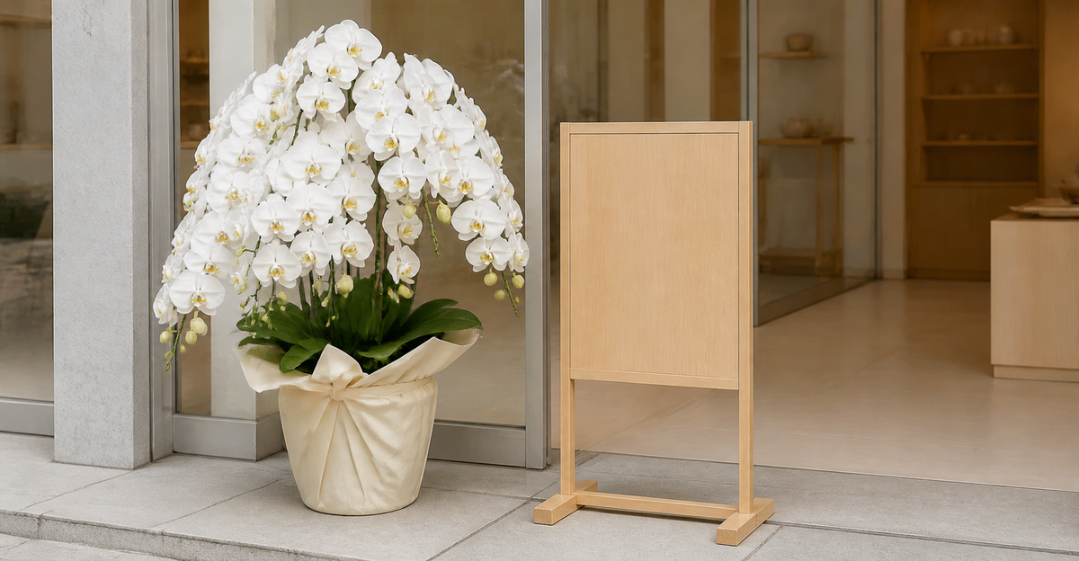 白い胡蝶蘭の鉢植えと木製の立て看板